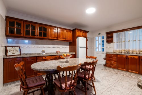 Spacious kitchen and dining area in Azul Infinito Casa, Arco da Calheta with wooden cabinetry, granite countertops, round