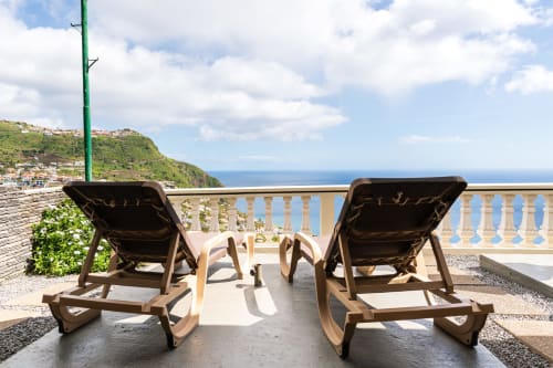 Two sun loungers on a terrace with sea views at Azul Infinito Casa in Arco da Calheta, Portugal, overlooking coastal cliffs