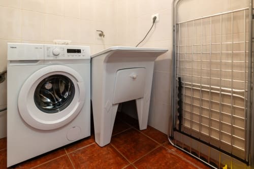 Modern laundry room with white washing machine, dryer, and glass shower enclosure at Garry's Holiday Rentals in Portugal