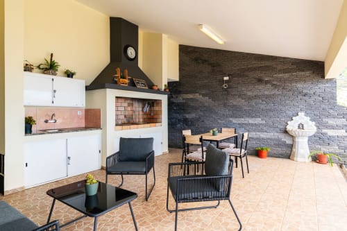 Modern living and dining area in Azul Infinito Casa apartment, Arco da Calheta, with black brick accent wall, kitchen, and
