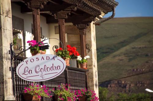 Posada La Colodra entrance with colorful flowers and traditional Spanish architecture overlooking mountain landscape