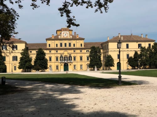 Palazzo Garibaldi, a grand yellow neoclassical palace in Parma with clock tower, manicured gardens and courtyard