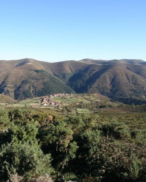Mountain valley village view with forested hills and traditional buildings at Posada La Colodra, Spain