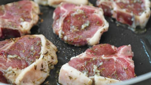 Raw steaks seasoned with herbs on a dark skillet at Posada La Colodra, Spain