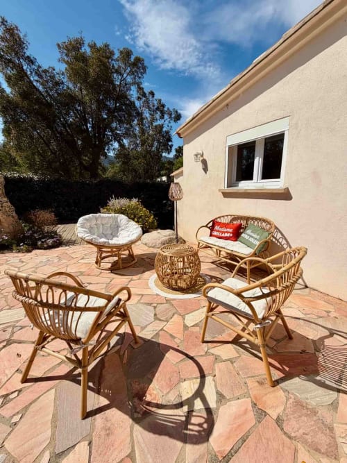 Terrasse ensoleillée à la Villa Noti, Les Villas d'A Storia à Porto-Vecchio, avec mobilier en rotin et vue sur les montagnes