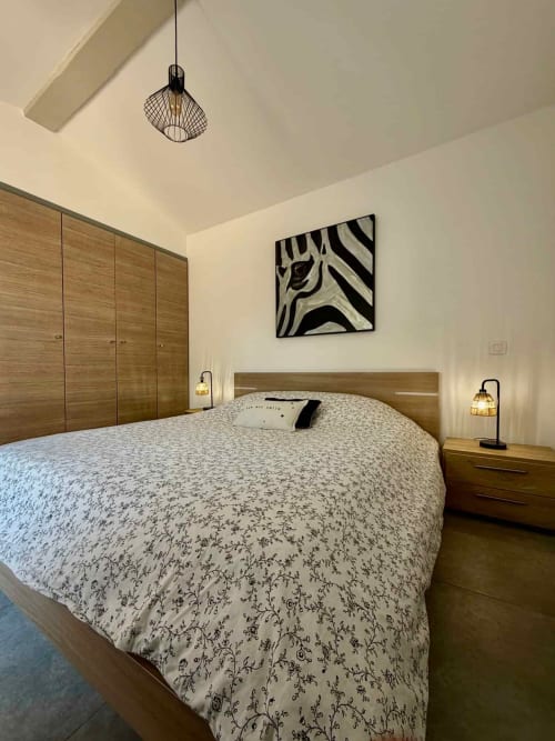 Chambre moderne aux Villas d'A Storia avec lit en bois, literie à motifs et tableau zèbre contemporain