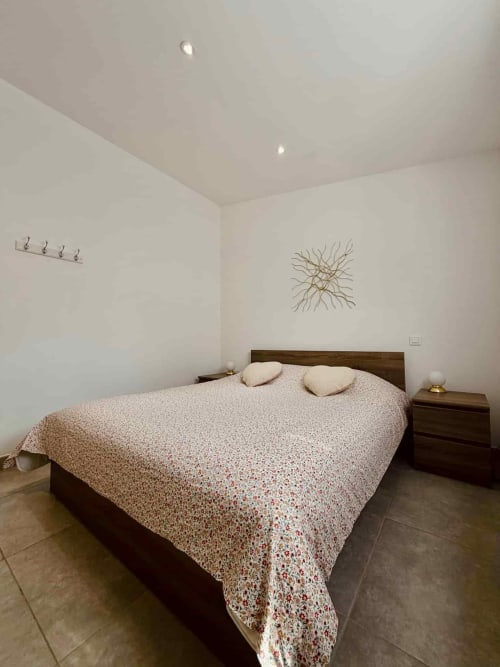 Chambre contemporaine aux Villas d'A Storia à Porto-Vecchio avec lit en bois, literie beige à motifs et murs blancs