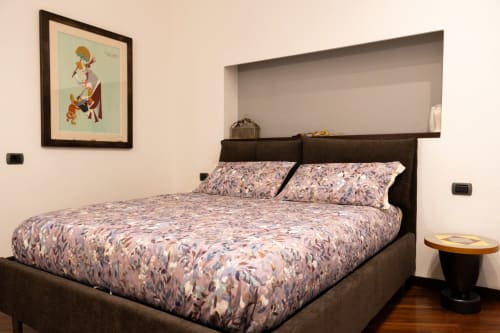 Camera Santiago di ROOMITO APARTMENTS Napoli con letto scuro, biancheria a motivi, opere d'arte murale e scaffalature integrate