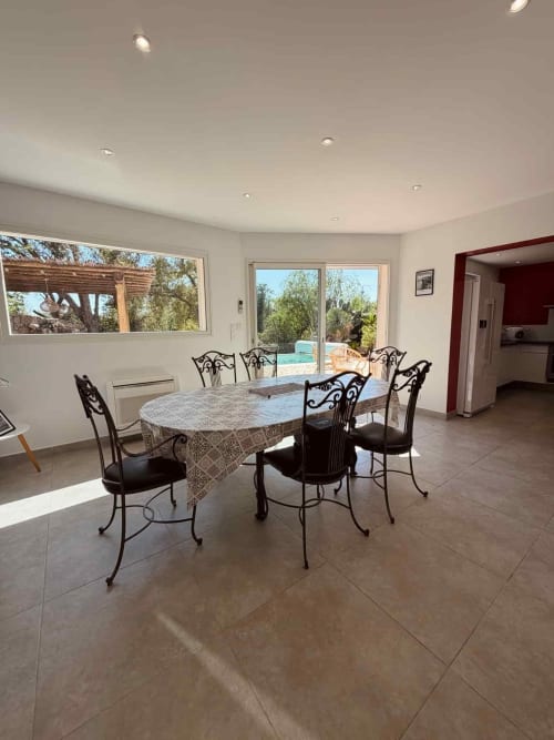 Spacieuse salle à manger avec table ovale et chaises en fer forgé surplombant la piscine privée aux Villas d'A Storia, Porto-Vecchio