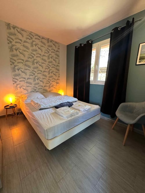 Chambre moderne à la villa Casa A Machja à Porto-Vecchio avec lit blanc, tête de lit graphique, rideaux noirs et ambiance chaleureuse