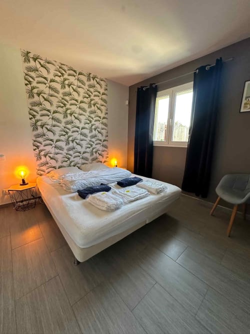 Chambre moderne aux Villas d'A Storia à Porto-Vecchio avec tête de lit palmée, lit blanc et ambiance chaleureuse