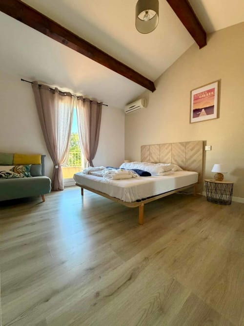 Spacieuse chambre principale de la villa Casa Incantu à Porto-Vecchio, avec plafond voûté, poutres en bois et vue sur le jardin