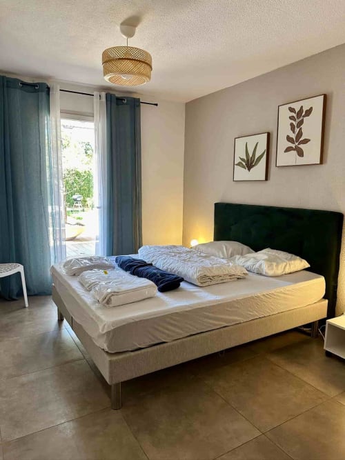 Chambre moderne de la villa Casa Incantu aux Villas d'A Storia, Porto-Vecchio, avec lit à tête de lit noire et lampe suspendue tressée