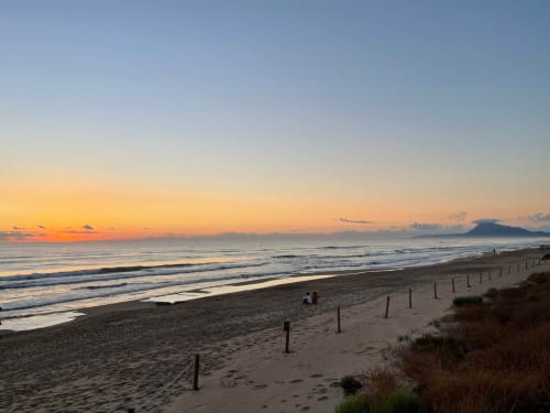 Sonnenaufgang über dem Strand von Benissa mit goldenem Himmel, Wellen und fernem Berg bei Casa Gallinera, Spanien