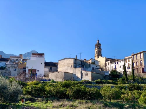 Dorf Benissivà mit dem Casa Gallinera, Kirchturm und umgebenden mediterranen Gebäuden sowie Olivenbäumen