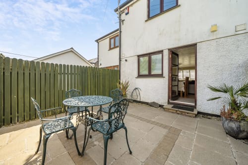 Private patio with wrought iron dining set overlooking green fenced garden at Archies Place cottage in Padstow