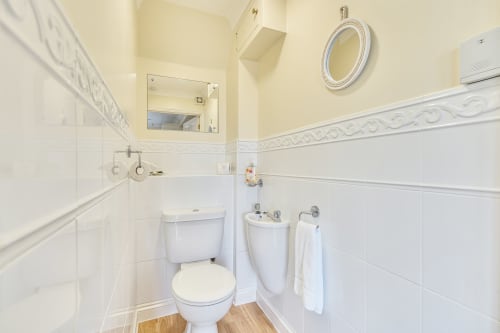 Clean white bathroom in Archies Place cottage with toilet, pedestal sink, and tiled walls at 2 Doves Holiday Property,