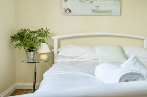 Clean white bedroom with plants and lamp at Archies Place cottage in Padstow, Exeter