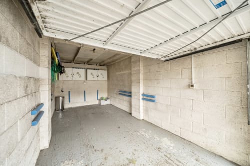 Empty garage interior with concrete block walls, metal roof panels, blue handles, and storage area at Archies Place cottage
