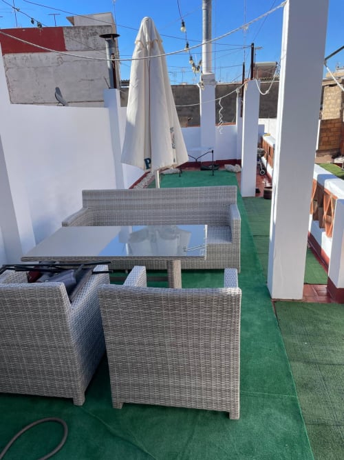 Rooftop terrace at Algemesi Home with wicker seating, glass table, and umbrella overlooking the city