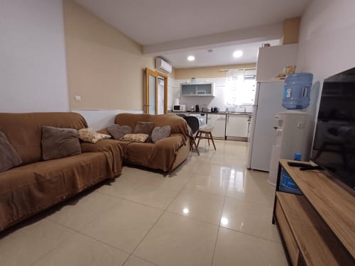Open-plan living area at Algemesi Home apartment with brown sofas, kitchen, TV, and modern amenities in Algemesi, Spain