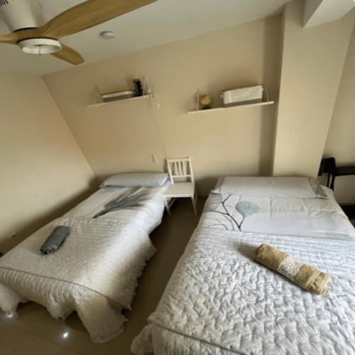 Two twin beds in bright attic bedroom at Algemesi Home apartment with ceiling fan and built-in shelving