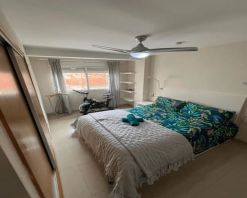 Modern bedroom in Algemesí apartment with queen bed, exercise bike, ceiling fan, window with city views, and contemporary