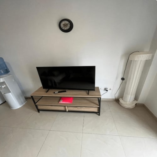 Living room in Algemesí Home apartment with TV on wooden stand, wall clock, and air conditioning unit