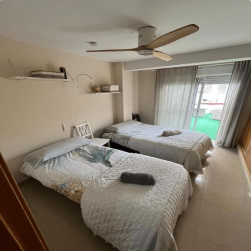 Twin bedroom with beige bedding, ceiling fan, and glass doors opening to a terrace at Algemesi Home apartment, Spain