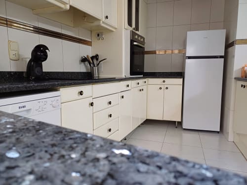 Modern kitchen in San Jose Luminoso apartment at Algemesi Home with cream cabinets, black granite countertop, white