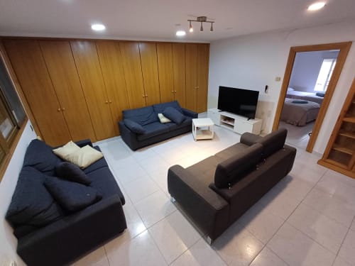 Spacious living room in San Jose Luminoso apartment, Algemesi, with dark sofas, TV, wooden wardrobes, and tiled flooring