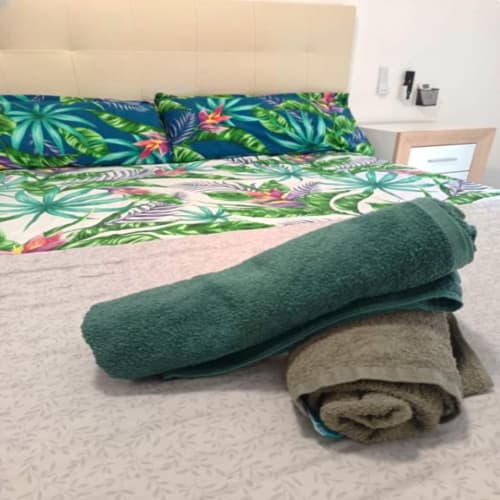Folded towels on bed with tropical bedding in Algemesi Home apartment San Jose Luminoso room