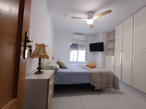 Bright bedroom at Algemesi Home with double bed, ceiling fan, wall-mounted TV, white closets, and balcony access in Algemesi,