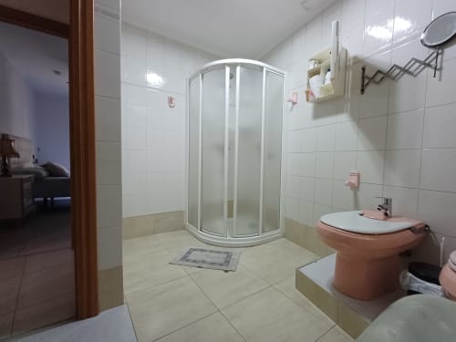 Modern bathroom in Algemesi apartment with shower, pink bidet, white sink, and tiled flooring