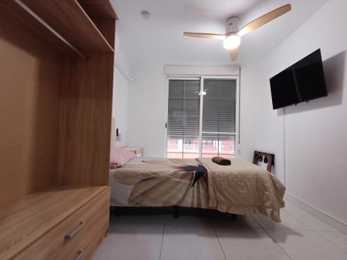 Modern bedroom at Algemesi Home with city view, ceiling fan, flat-screen TV, wooden wardrobe and bed
