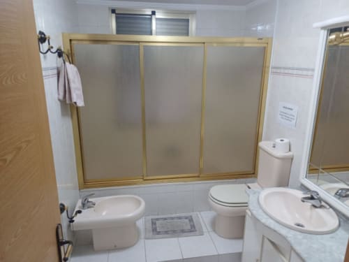 Bathroom in San Jose Luminoso apartment at Algemesi Home, featuring bathtub with glass enclosure, toilet, bidet, and sink