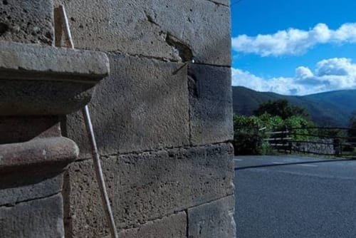 Stone archway at Posada La Colodra with mountain views and blue sky, Los Tojos Spain