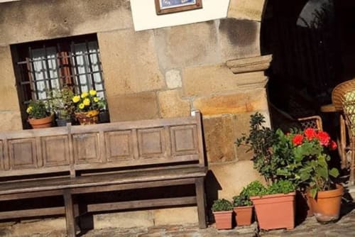 Rustic courtyard at Posada La Colodra with wooden benches, potted flowers, and stone walls