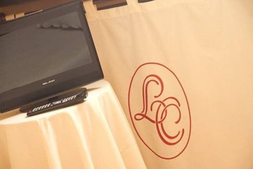 Posada La Colodra hotel room detail showing TV and decorative red emblem on beige wall