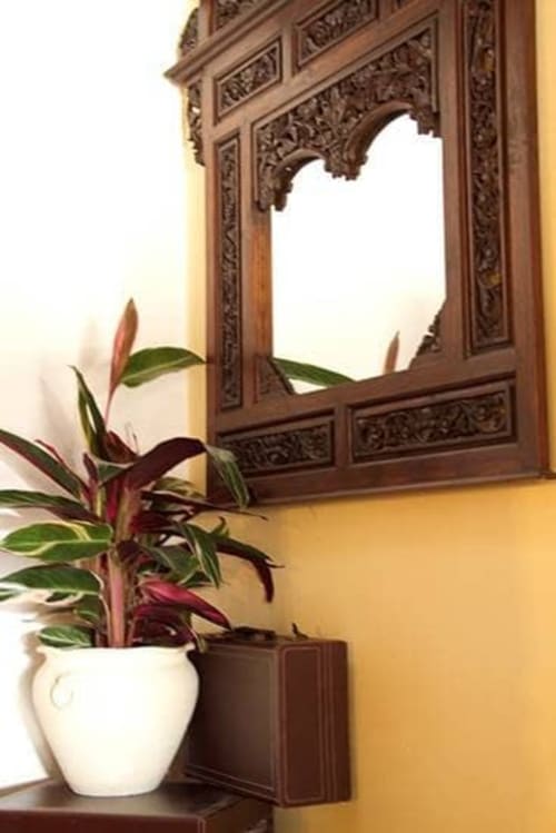 Ornate wooden mirror with decorative carvings above a potted plant at Posada La Colodra in Los Tojos