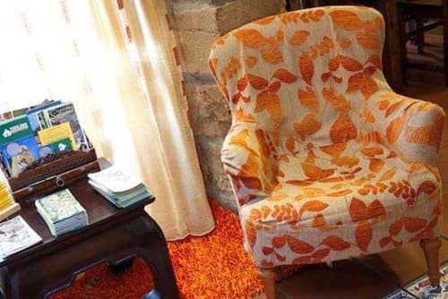 Cozy reading nook at Posada La Colodra with orange leaf-patterned armchair and dark wooden desk by window in Los Tojos