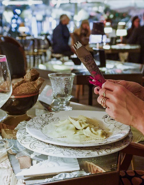 Woman dining at Palazzo Garibaldi Parma, elegant plated pasta dish with decorative china and glassware