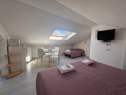 Spaziosa camera mansardata a B&B Residenza Leonardo, Falconara Marittima, con letti, scrivania, TV e lucernario
