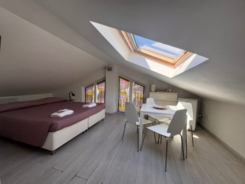 Moderna habitación en buhardilla con tragaluces, vistas al mar, cama doble, escritorio, mesa de comedor y suelo de madera en B&B Residenza