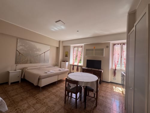 Amplia habitación triple en B&B Residenza Leonardo con cama, mesa de comedor, TV y vistas al jardín en Falconara Marittima