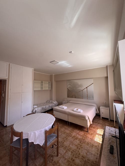 Habitación triple en B&B Residenza Leonardo, Falconara Marittima con dos camas, mesa redonda, armarios y vistas al jardín