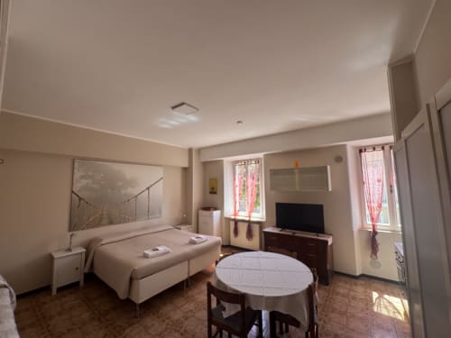 Luminosa habitación triple en B&B Residenza Leonardo con cama, TV, mesa de comedor y vistas al jardín en Falconara Marittima
