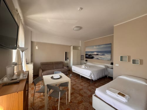 Amplia sala familiar en B&B Residenza Leonardo en Falconara Marittima con sofá, dos camas, comedor y vista a las montañas