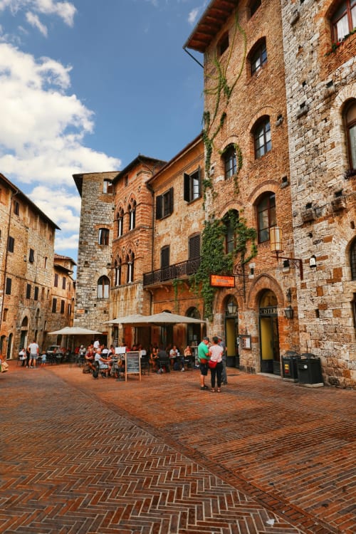 Medieval brick courtyard at Borgo di Erboli, Cavriglia, Italy, with stone buildings and outdoor café seating