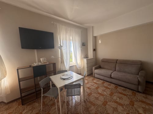 Habitación moderna en B&B Residenza Leonardo en Falconara Marittima con sofá cama, TV de pantalla plana, mesa de comedor y vistas a la montaña